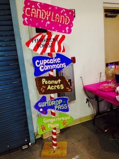 there are many signs on the pole in front of the door that say candy land and cupcake commonss