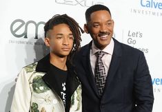 two men standing next to each other on a red carpet