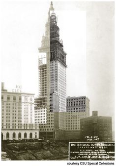 an old black and white photo of a tall building under construction in the middle of a city