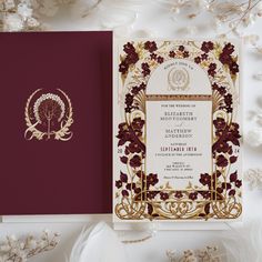 an ornate wedding card with gold foil on it and maroon paper in the middle, surrounded by white flowers