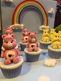 there are many cupcakes with teddy bears on them and a rainbow in the background