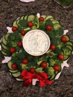 broccoli, cucumbers and tomatoes arranged on a platter with dip