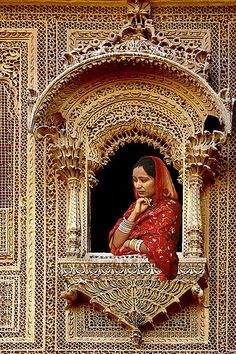 a woman in red is looking out the window