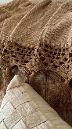 a brown blanket sitting on top of a bed next to a pillow and two pillows