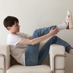 a man sitting in a white chair with his legs crossed and feet propped up on the armrest