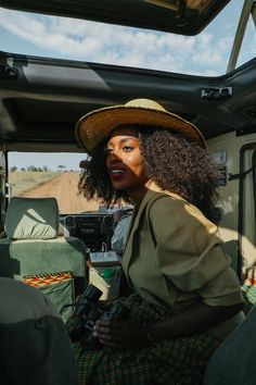 a woman sitting in the back of a truck with a hat on her head and holding a camera