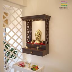 a small shrine is displayed on the wall next to a table with fruit and flowers