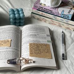 an open book sitting on top of a bed next to a pen and some other items