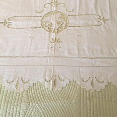 an old white bed spread with embroidered designs on it