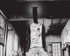 black and white photograph of a man standing on top of a bed in a room