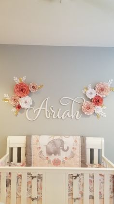 a baby's crib with flowers on the wall and name sign above it