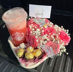 a cup of coffee and some candy on the back of a car with pink roses