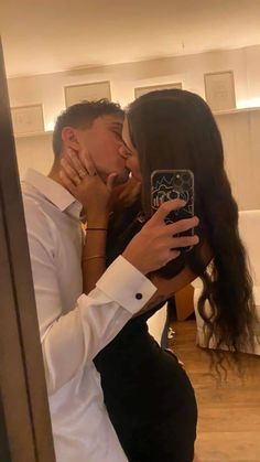 a man and woman taking a selfie in front of a mirror