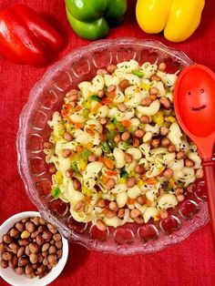 a bowl filled with macaroni and cheese next to some vegetables on a red table