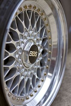 the front wheel of a car with beaded spokes and an emblem on it