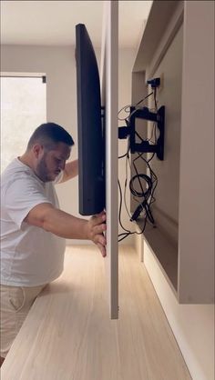 a man is holding up a television in the living room with his feet on the wall