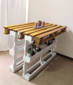 a table made out of wooden pallets with bottles on the top and two planters below