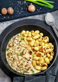 a pan filled with pasta and mushrooms on top of a table next to some vegetables