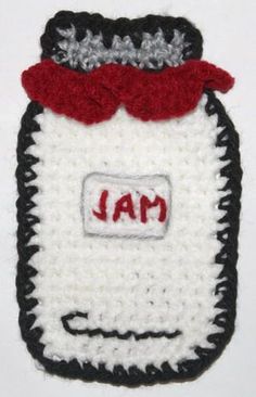 a crocheted jar with the word jam on it and a red bow around its neck