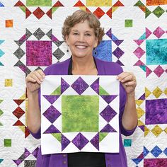 a woman holding up a piece of quilt