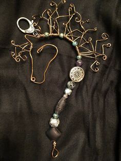 a necklace with various items attached to it on a black cloth covered surface, in the shape of a horse's head