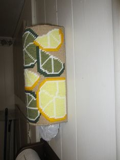 a towel hanging on the wall next to a toilet paper dispenser filled with lemons and limes