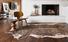 a living room with a fireplace, chair and rug