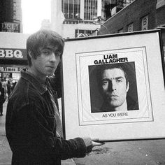 a young man holding up a poster with an image of the actor as if he was in front of him