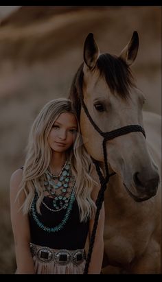 a beautiful blonde woman standing next to a horse