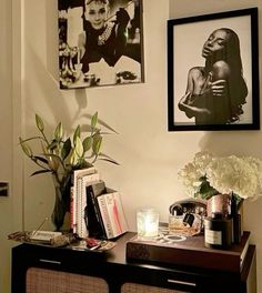 a table with flowers, candles and pictures on the wall above it in a living room