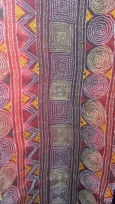 an african print fabric with circles and lines on red, yellow and orange colors in the background