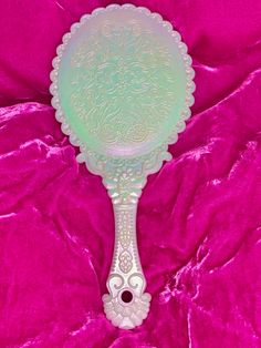 an ornate glass mirror on a pink velvet background