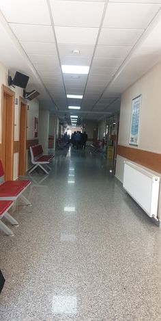 an empty hallway with red chairs and white walls