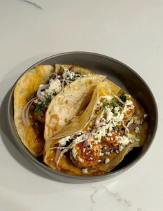 some tacos are sitting in a bowl on a white counter top and it looks like they have been made from tortillas