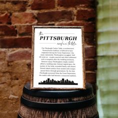 a sign on top of a wooden barrel in front of a brick wall that reads the pittsburgh super city