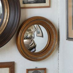 there is a mirror on the wall next to two framed pictures and an old photo