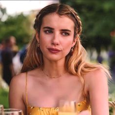 a woman in a yellow dress sitting at a table with two glasses of orange juice