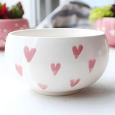 two bowls with hearts painted on them sitting on a table next to some strawberries