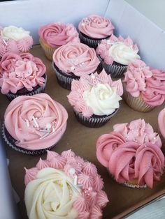 a box filled with lots of pink and white cupcakes