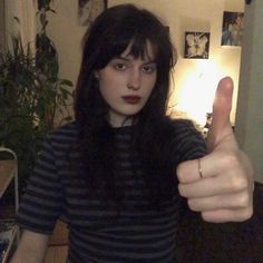 a woman giving the thumbs up sign in her living room