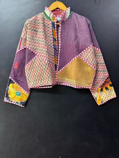 a colorful jacket hanging on a hanger next to a black wall with an orange and yellow design