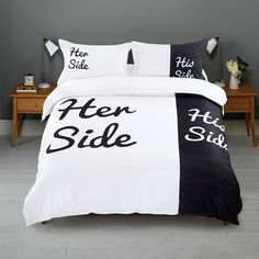 a bed with black and white pillows on top of it next to a wooden table