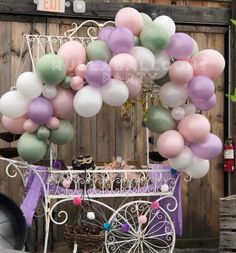 a cart with balloons attached to it in front of a wooden fence