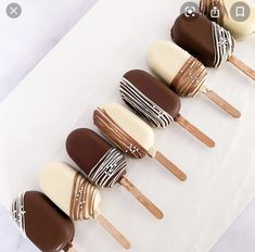 chocolate covered desserts are lined up on a white platter with wooden spoons