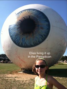 a woman standing in front of an eyeball with the caption ella living it up in the panopticon