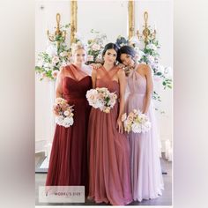 three bridesmaids pose for a photo in front of a floral backdrop and mirror