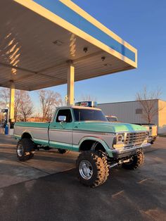 a green and white truck parked in front of a gas station under a blue sky