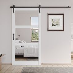 an open sliding door in a bedroom with white walls and hardwood floors, along with a rug on the floor