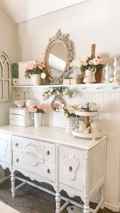 a white dresser sitting next to a mirror on top of a wall