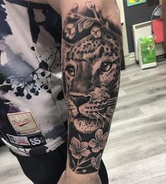 a man with a tattoo on his arm that has a leopard and flowers on it